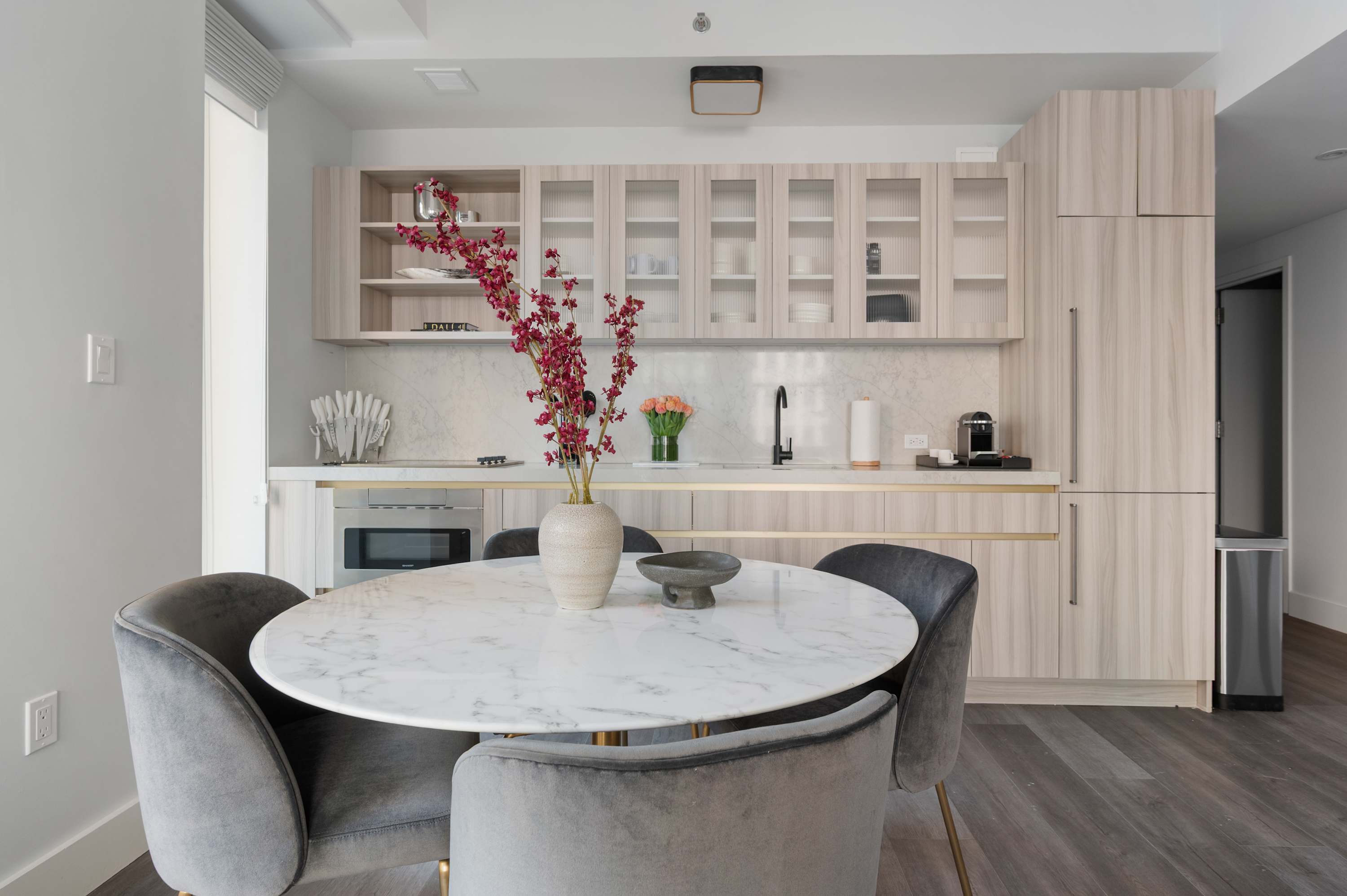 A modern kitchen with a marble table and gray chairs in a suite at 17 John.