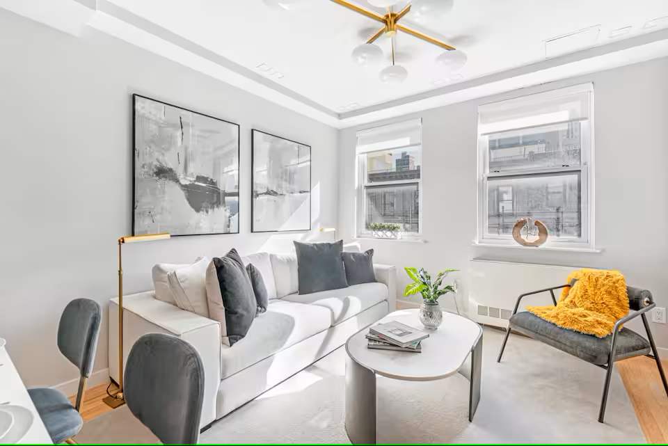 The living room of an apartment at The Sixty Two with a white couch and window.
