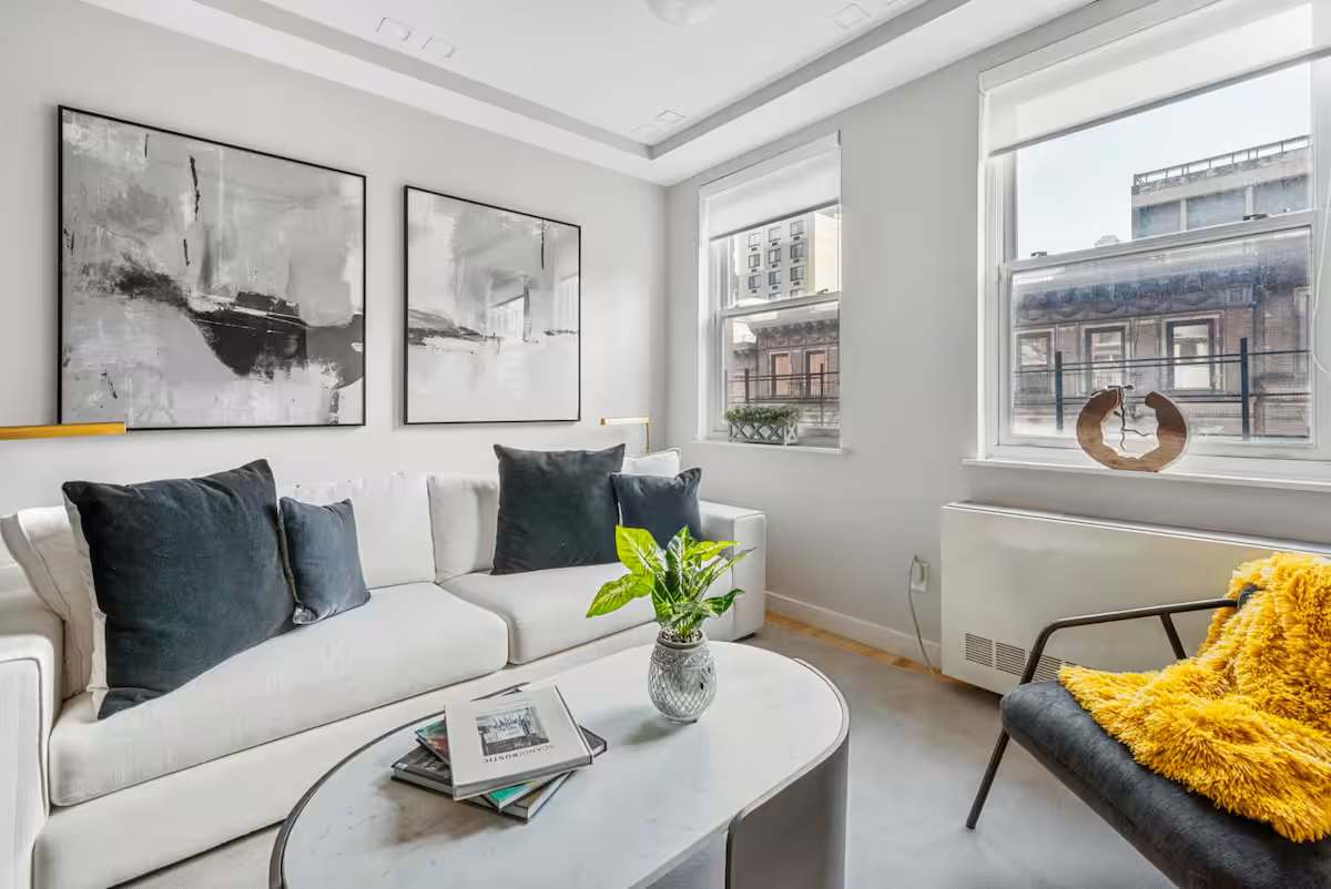 White living room with a couch, coffee table, and two windows in a Sixty Two apartment.