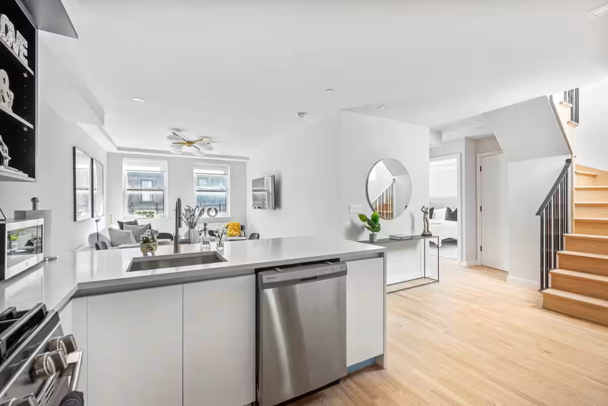 Kitchen in an apartment at The Sixty Two with white cabinets, wooden floors and stainless steel appliances.