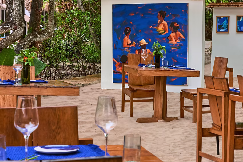 Beachside restaurant tables with wooden chairs and blue tableware