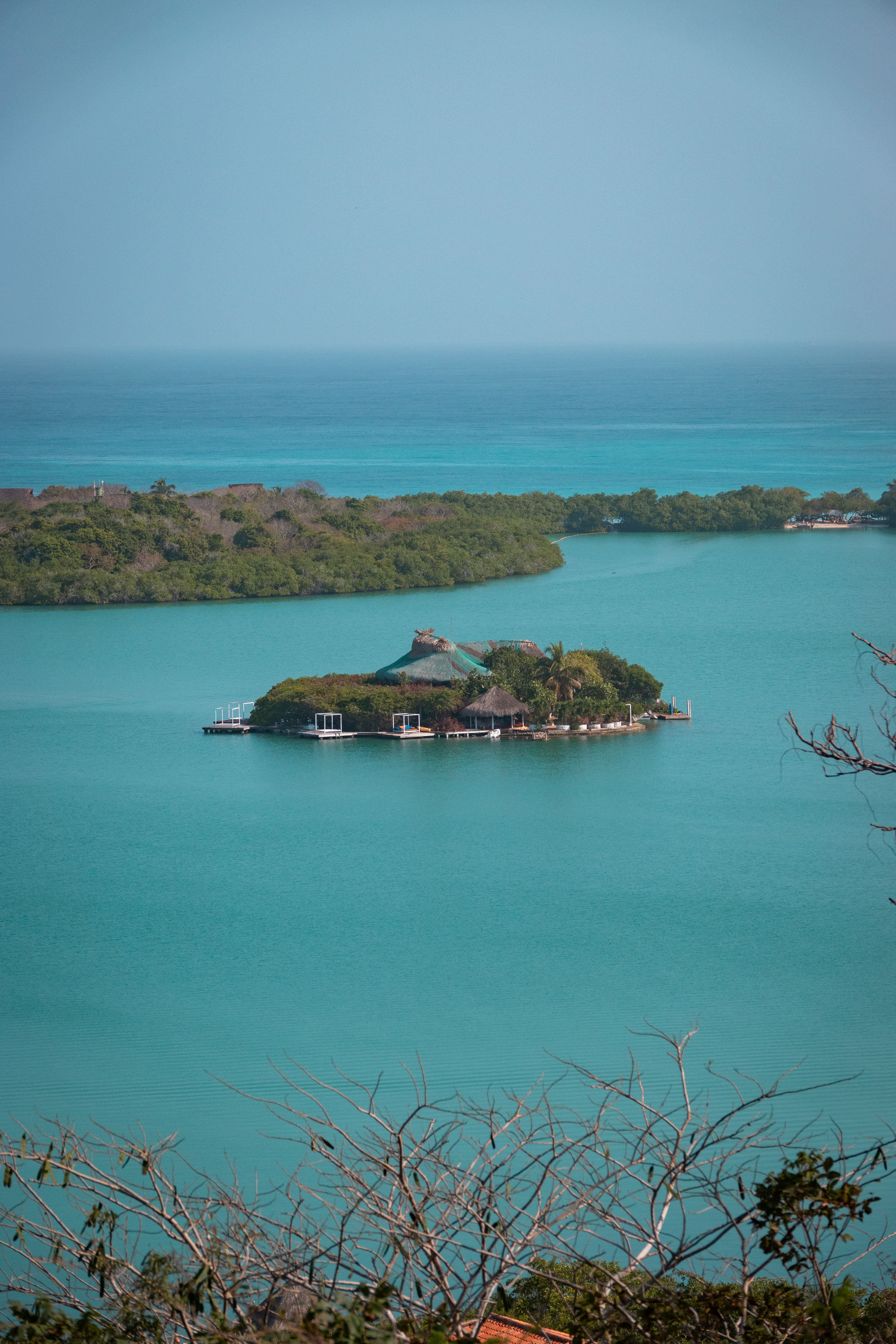 Aerial view of a small island with a hut and dock in blue water off Barú