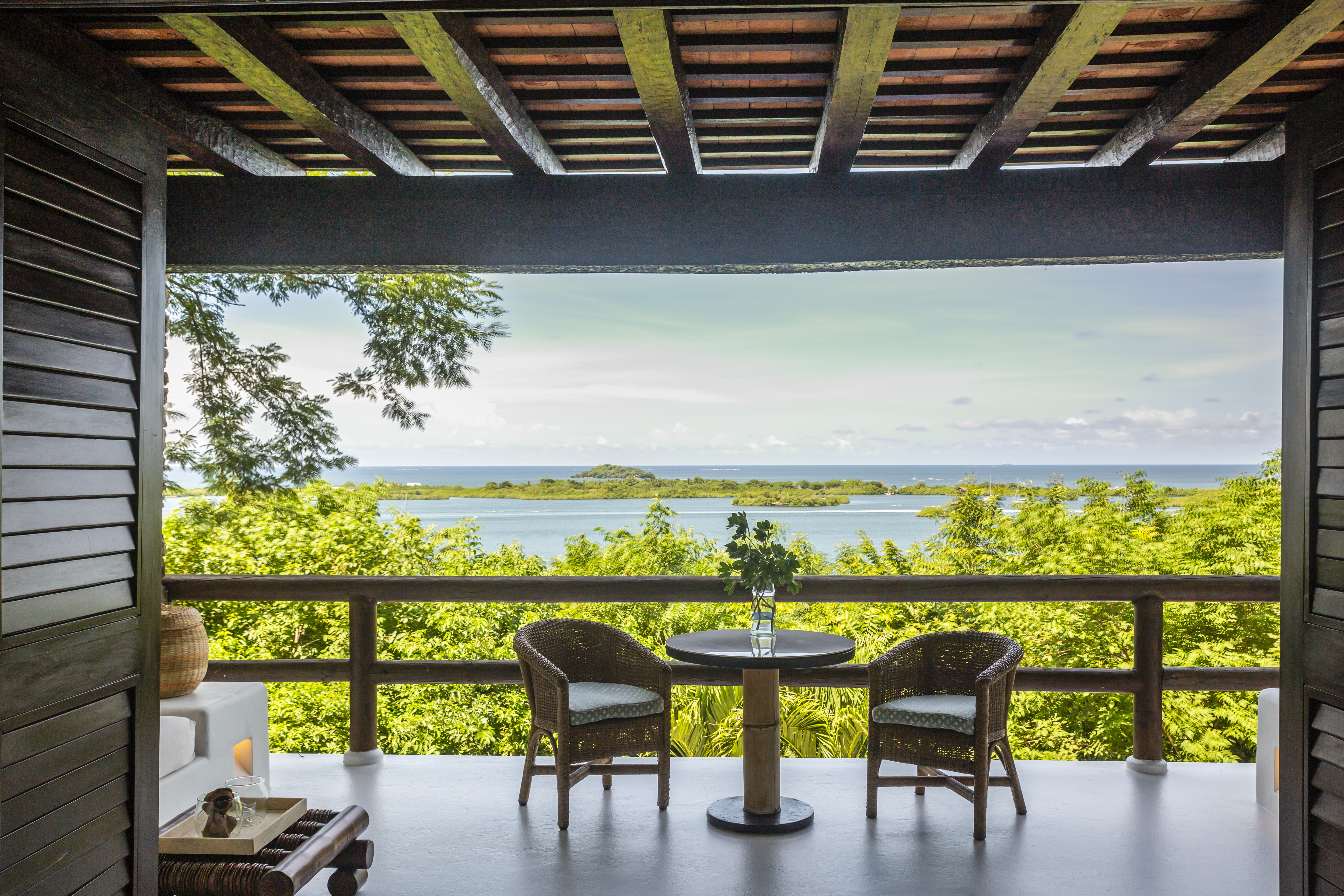 Un balcón con una mesa, sillas y una vista sobre el agua en la Bahía de Cholón