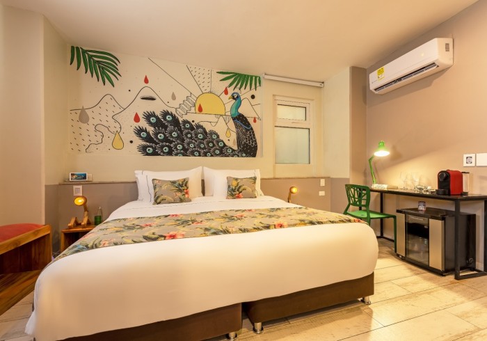 Una de nuestras habitaciones con un mural colorido pintado a mano y una silla verde