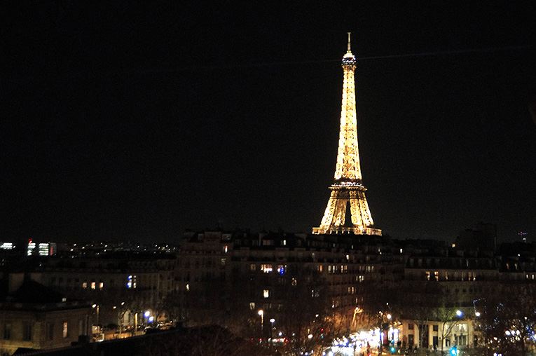 La tour Eiffel illuminée la nuit au-dessus des toits parisiens
