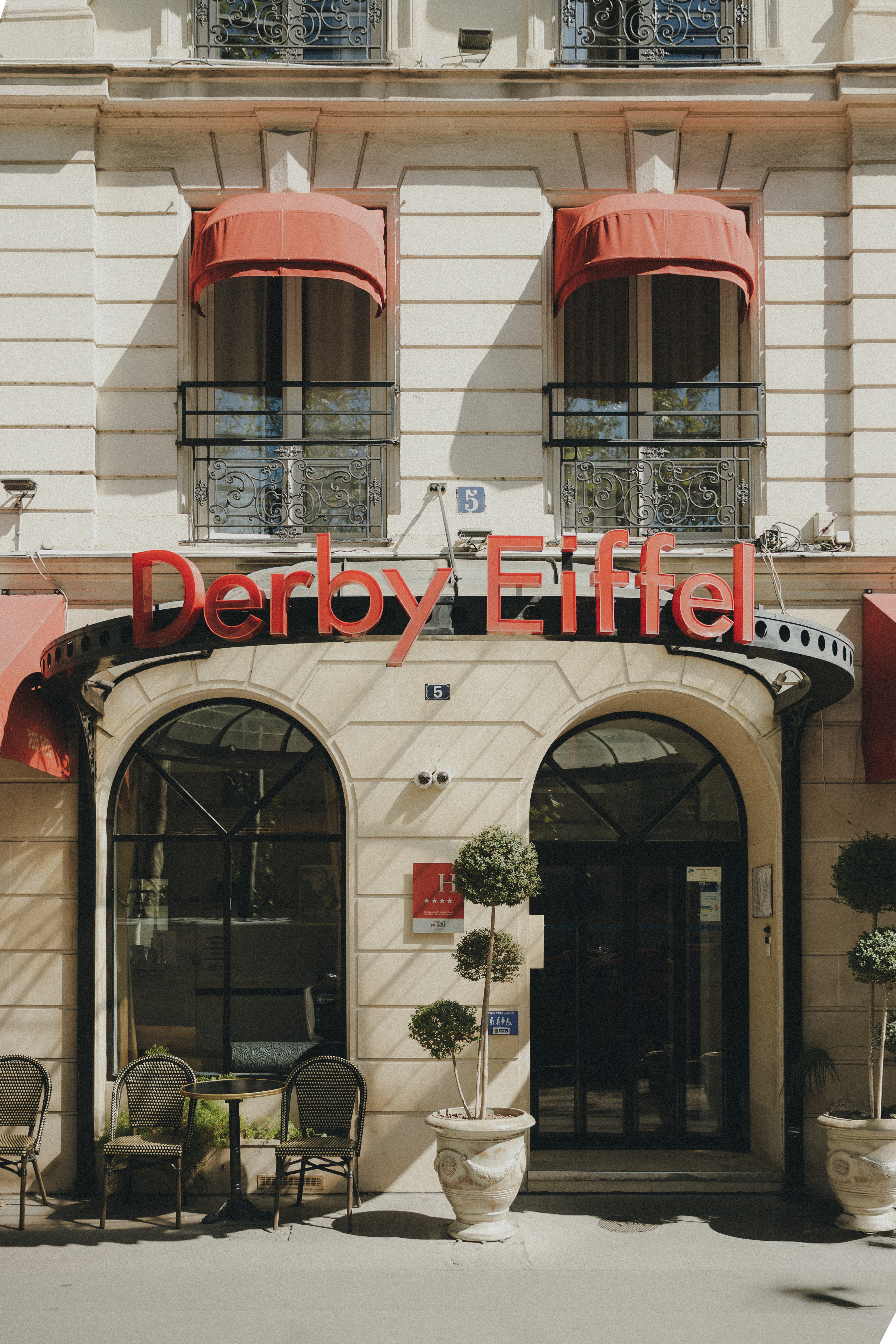 Facade of the Derby Eiffel hotel with its red awnings and potted plants, avenue Duquesne.
