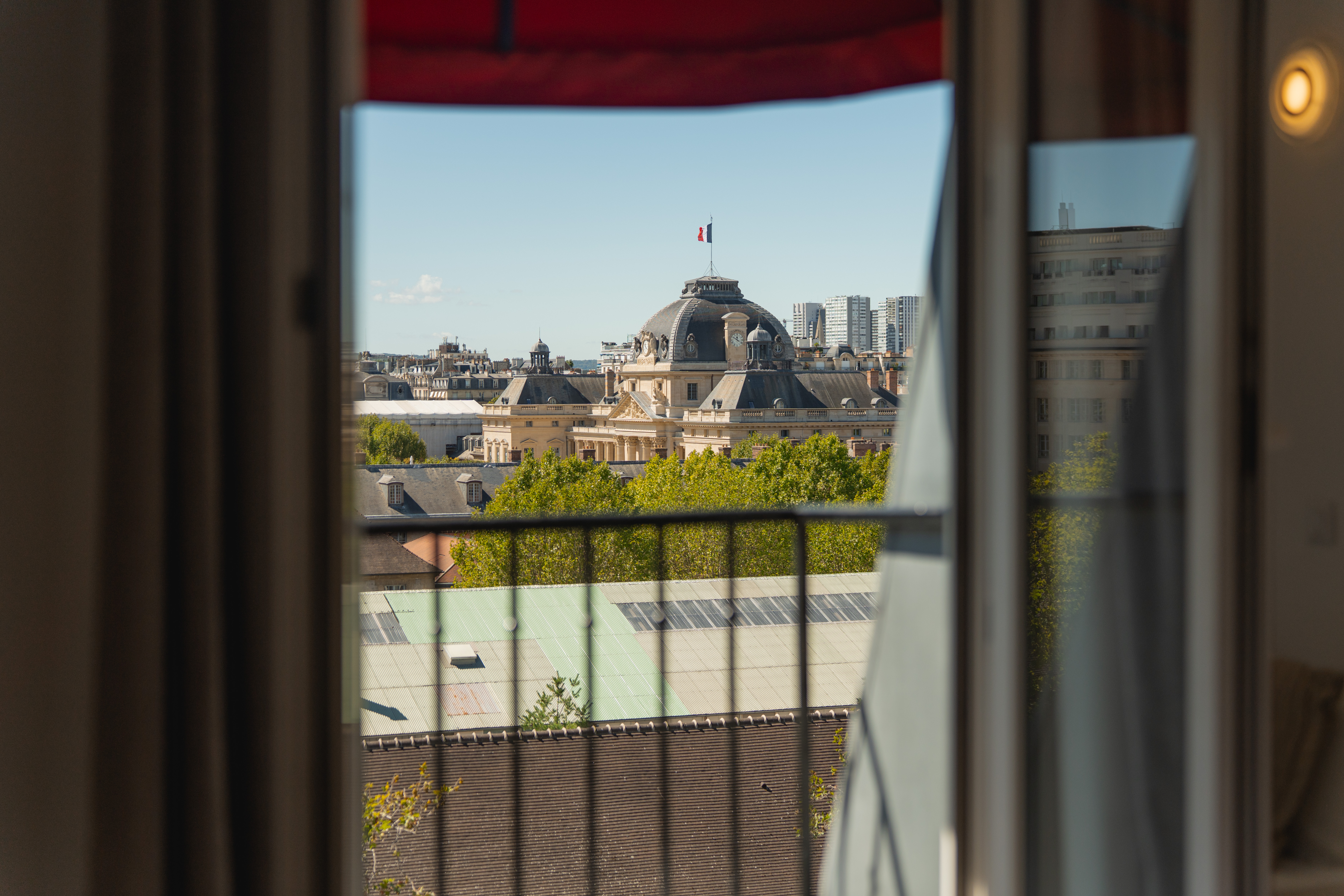 View from a hotel balcony of the 7th‑district rooftops and a dome topped with a flag