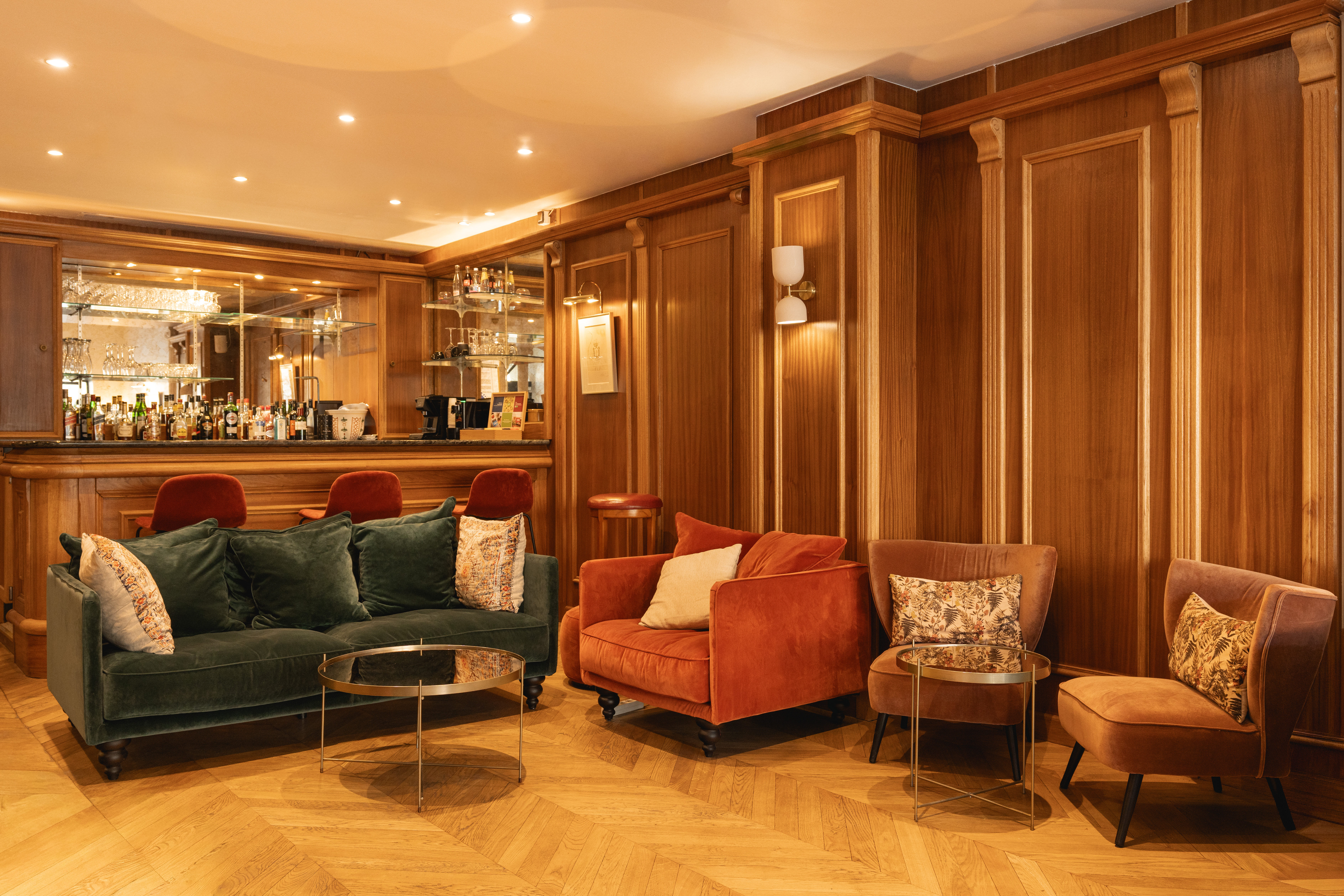 Our bar: a paneled lounge with velvet sofas under warm lamp light