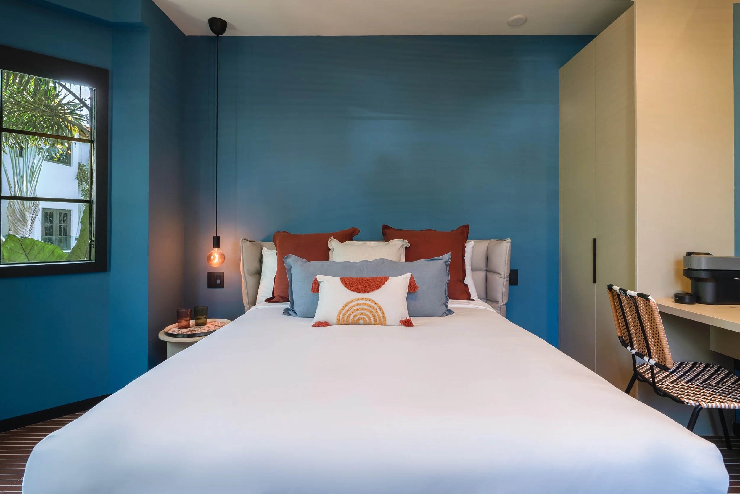 One of our bedrooms with blue walls, a white bed and decorative pillows