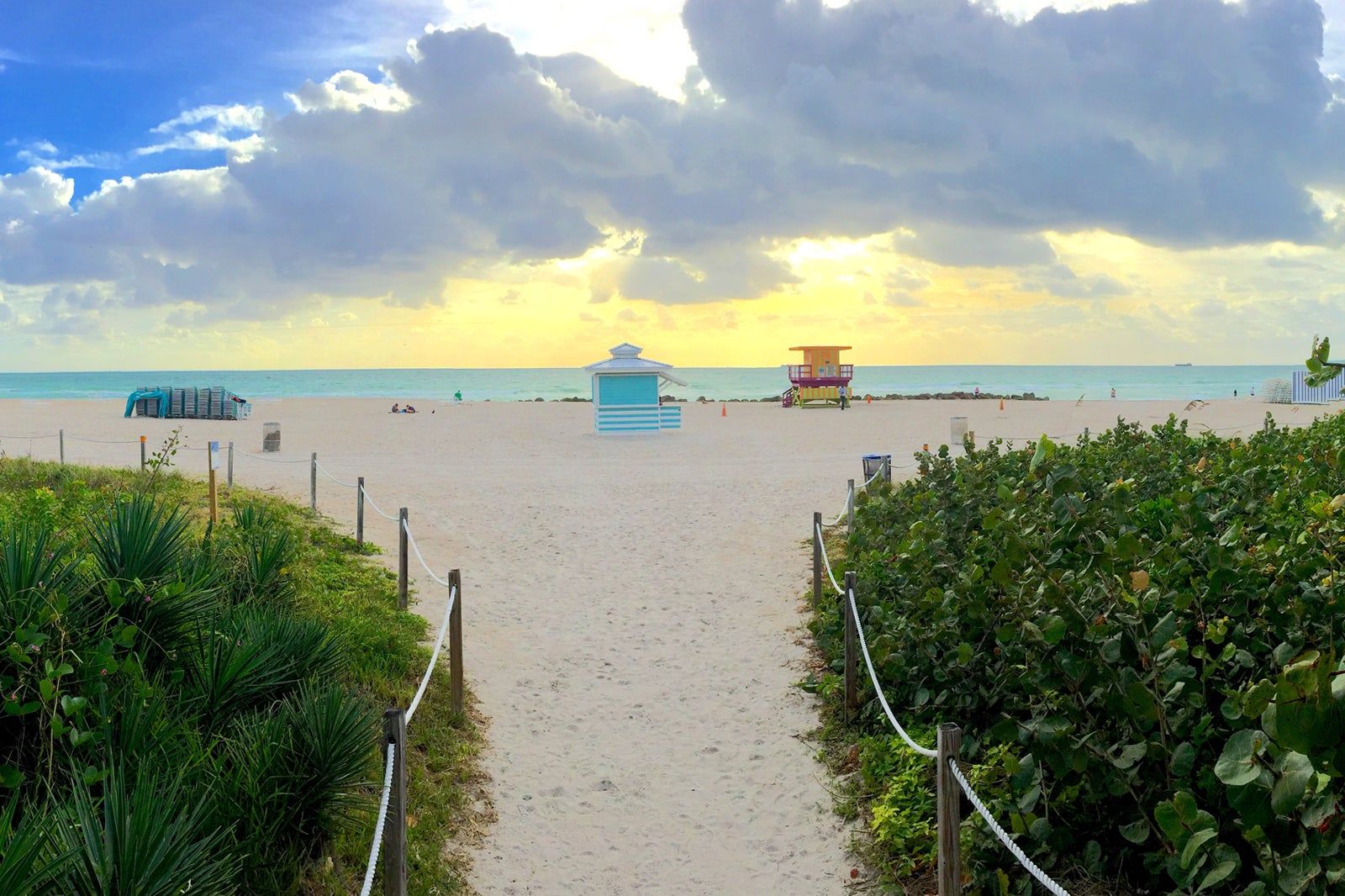 Beach with lifeguard stations under a sunset sky.