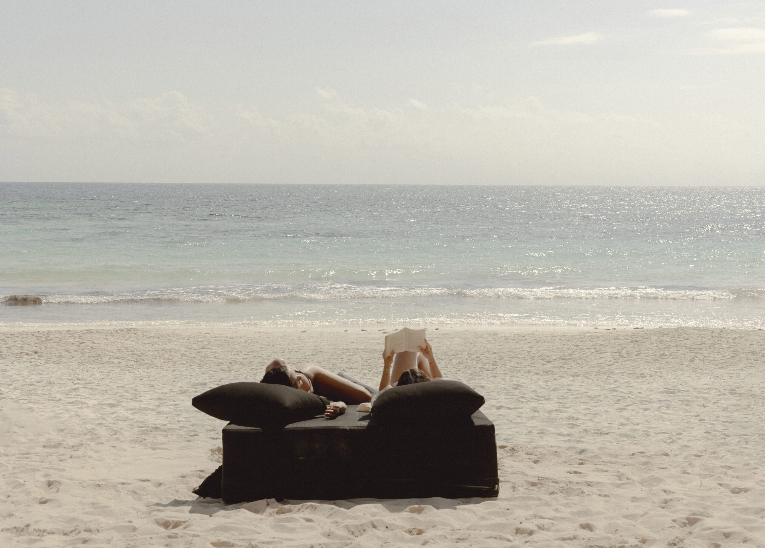A guest resting on a beach bed facing the sea