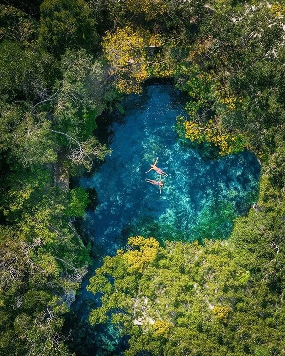 Aerial view of two people swimming in a cenote near Tulum
