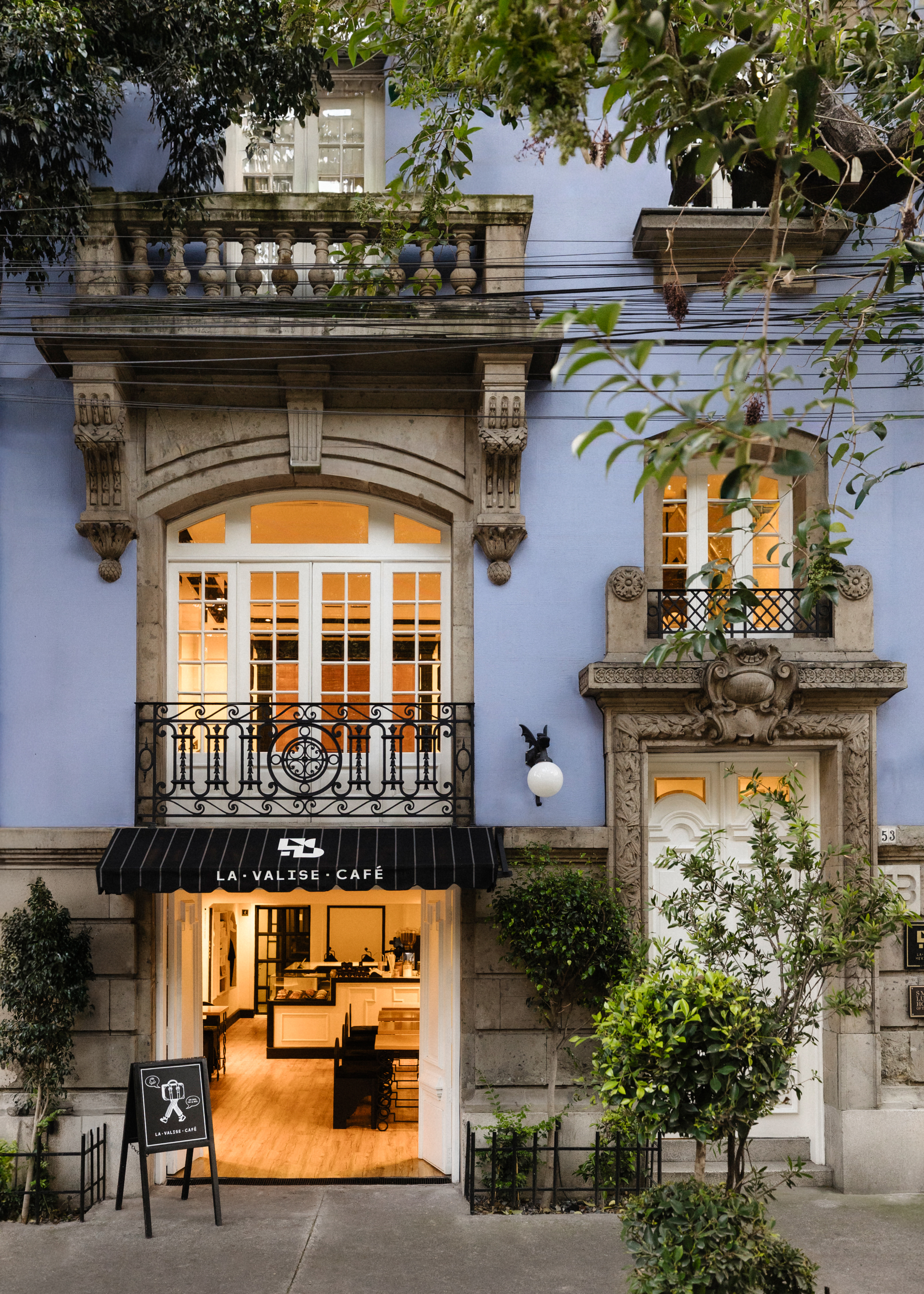 Illuminated façade and café entrance of La Valise Mexico City, a 1920s French-style townhouse on Tonalá in Roma Norte, at dusk