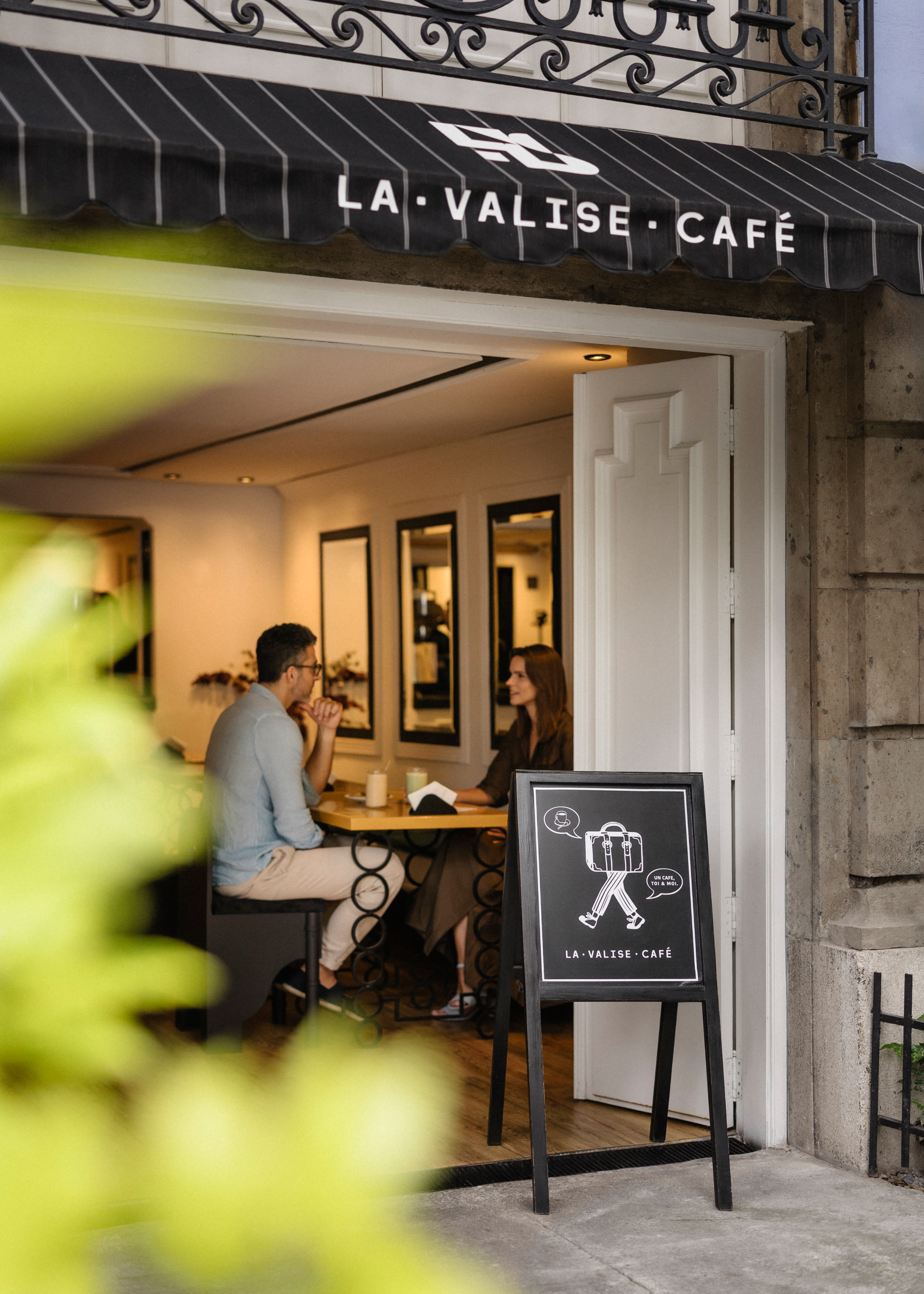 Morning coffee at the street-side entrance of La Valise Café in Roma Norte, with a chalkboard menu by the door