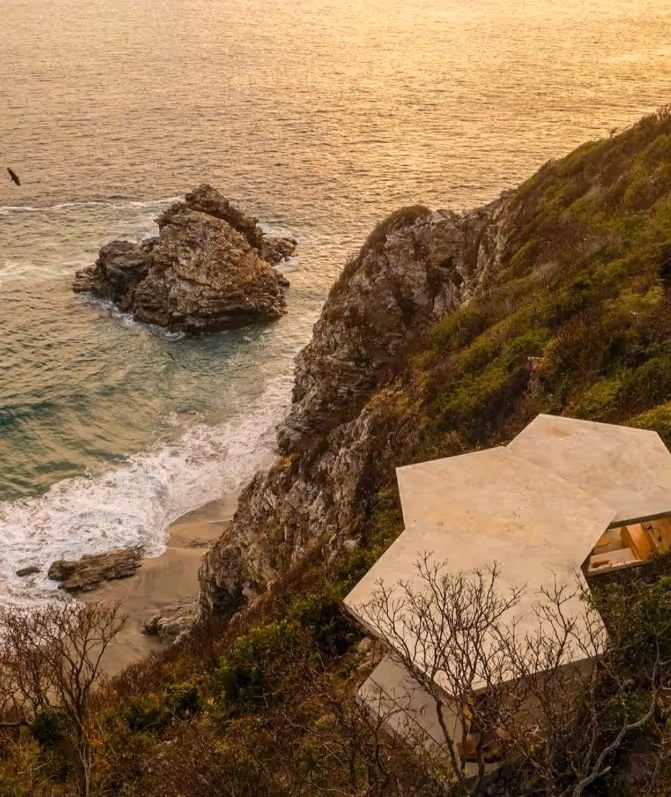 Vista aérea del edificio geométrico del restaurante de La Valise Mazunte sobre los acantilados con agua turquesa en la Reserva El Torón