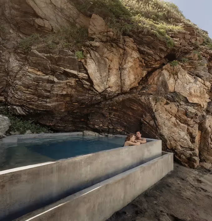 Alberca infinita construida bajo una pared de roca natural en La Valise Mazunte