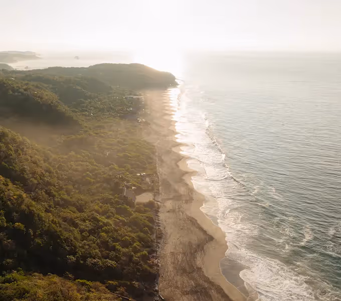 Vista aérea de la larga playa salvaje y el oleaje junto a la Reserva El Torón a la hora dorada
