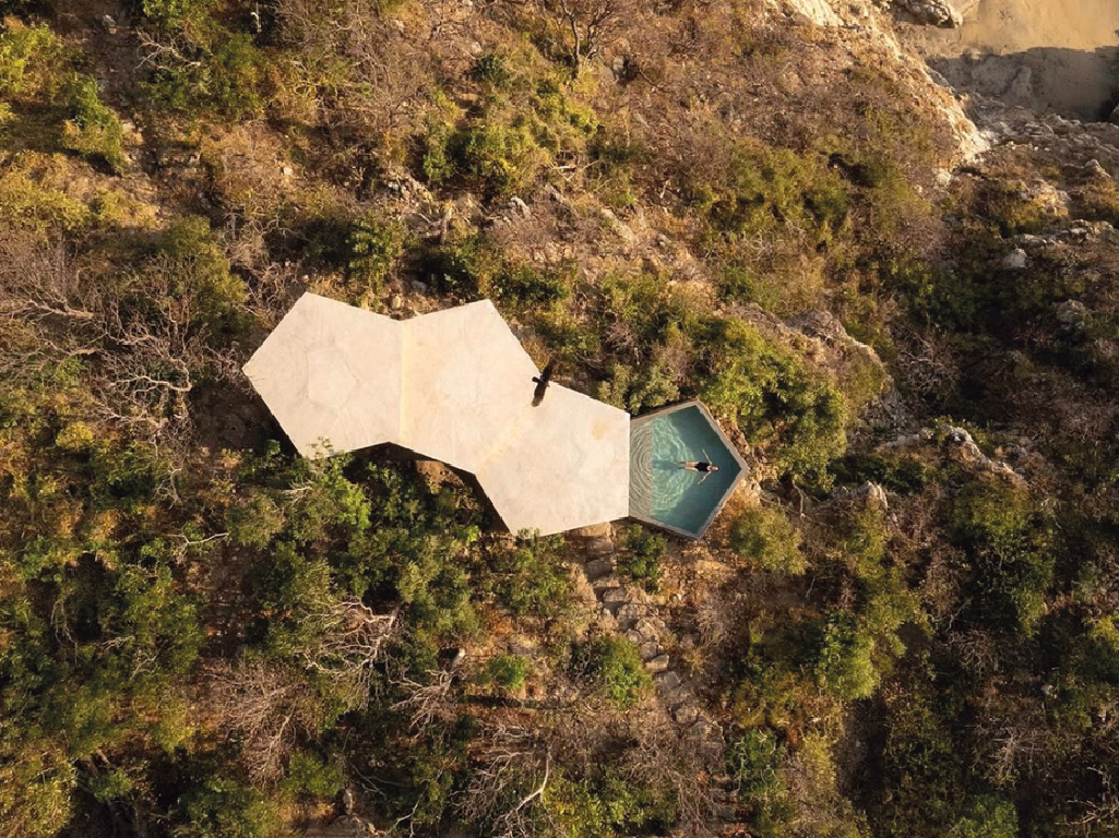 Vista aérea de los techos pentagonales y la alberca hexagonal de Villa Pentágonos en el acantilado boscoso