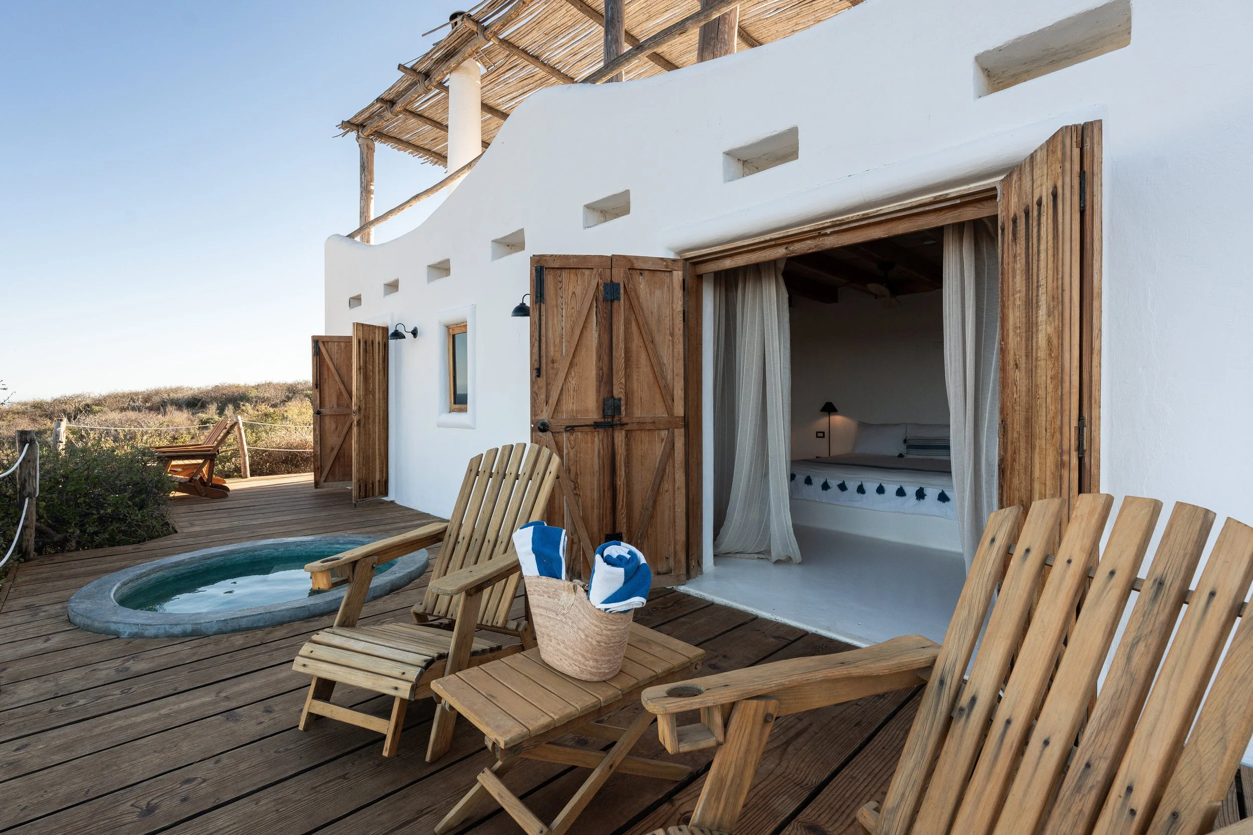 Terraza privada de la Private Cottage Two Bedroom con camastros de madera y una alberca frente a la costa