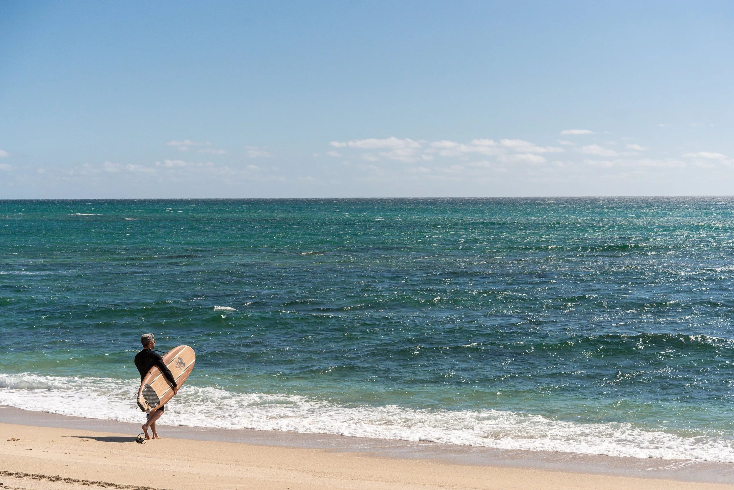 Surfer walking into the water on the East Cape